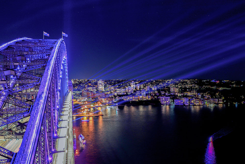 a bridge with lights and a city in the background