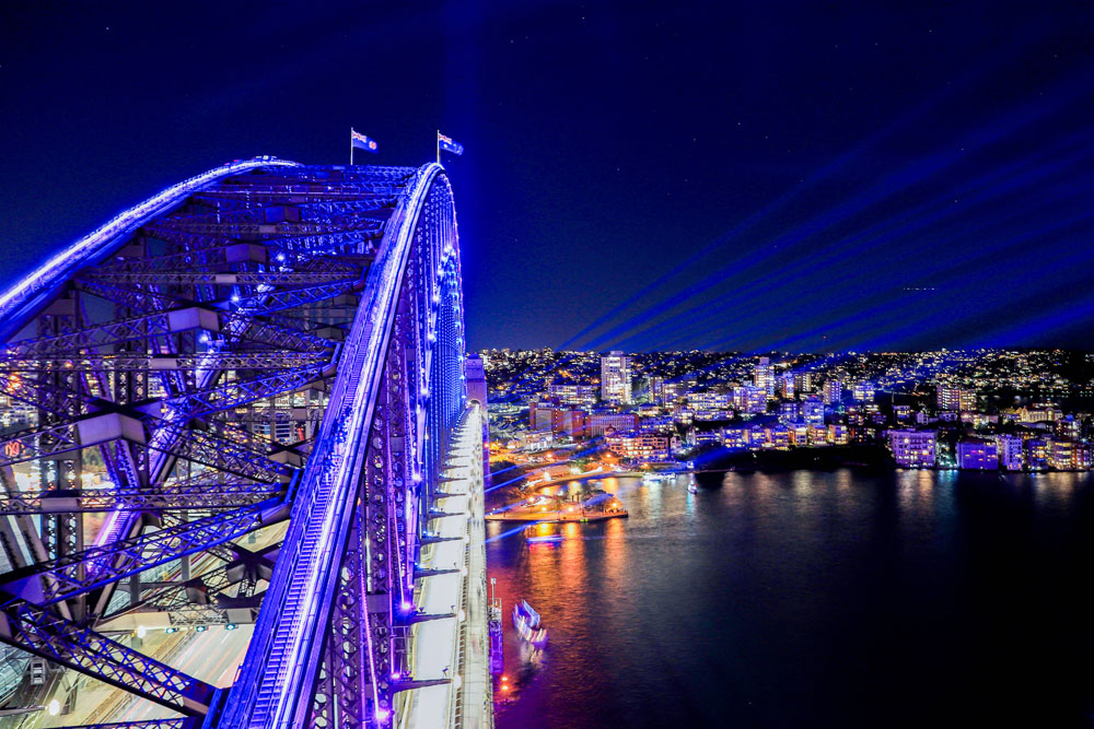 a bridge with lights and a city in the background